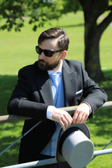 ACS Rental black morning suit with sky blue waistcoat and matching tie and pocket square. Model looks left and holds a grey top hat