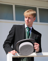 Model wears Black Tailcoat, Green Waistcoat & Grey Stripe Trousers Hire Package holding Top Hat