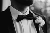 Close-up of tuxedo collar, black bow tie and buttonhole.