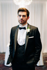 Groom in black slim fit tuxedo in a formal indoor setting.
