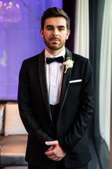 Groom in black slim fit tuxedo and bow tie.
