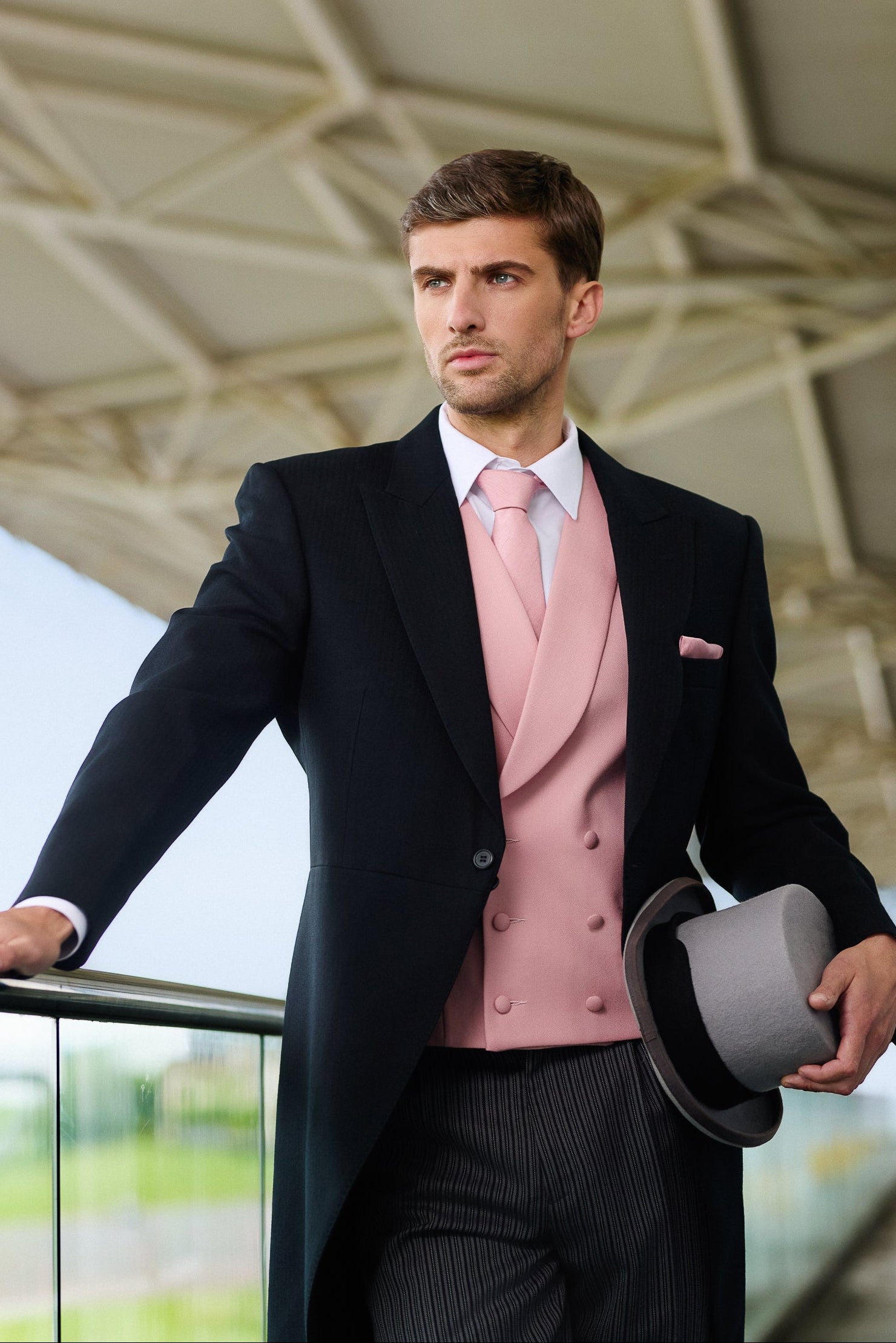 Man in Royal Ascot attire with a pink waistcoat holding a top hat, at Royal Ascot
