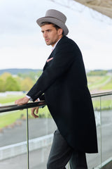 Man in a black tailcoat and grey hat standing on a balcony at Royal Ascot