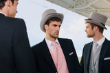 Three men in formal morning attire with top hats standing outdoors.