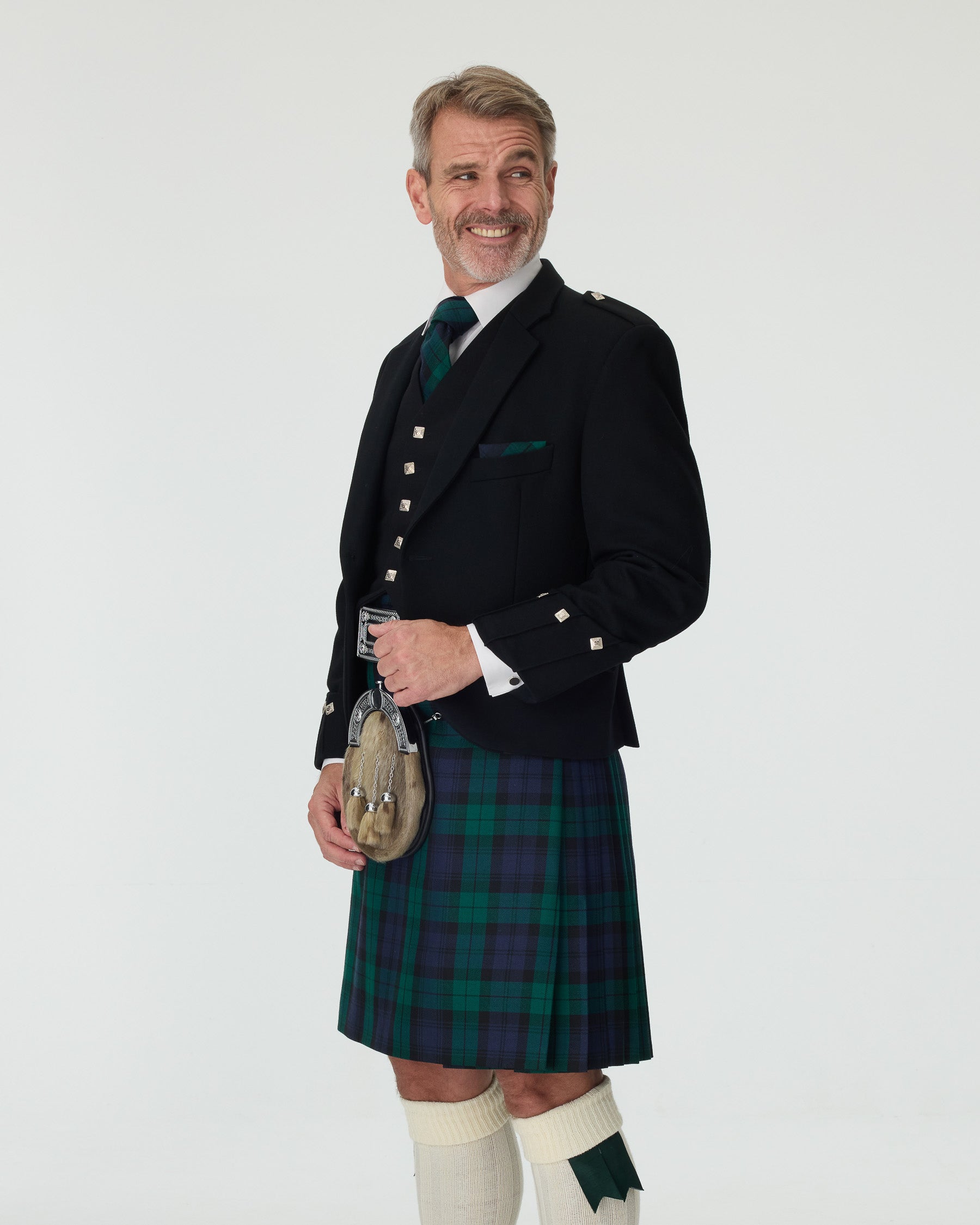 Man wearing a Black Watch kilt and Argyll Jacket with a white background