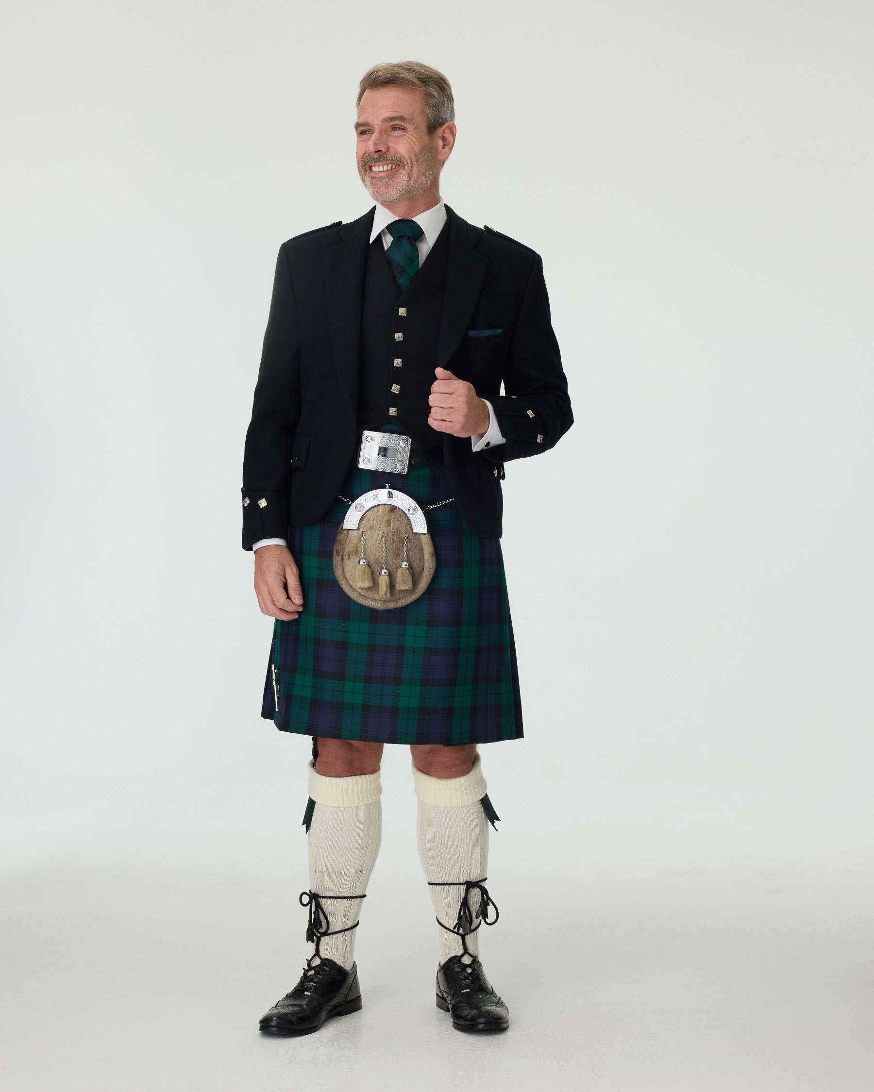 Man wearing a Black Watch kilt and Argyll Jacket with a white background