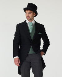 Man wearing a black tailcoat, green waistcoat, and top hat on a white background