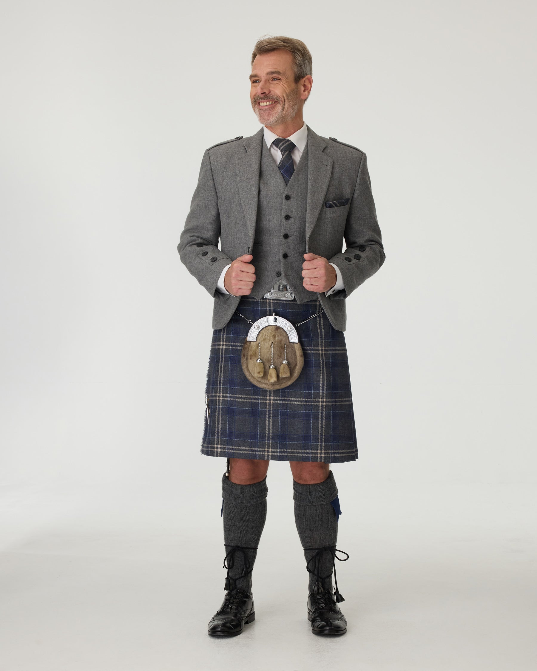 Man wearing a Highland Stor kilt with a charcoal tweed jacket on a white background