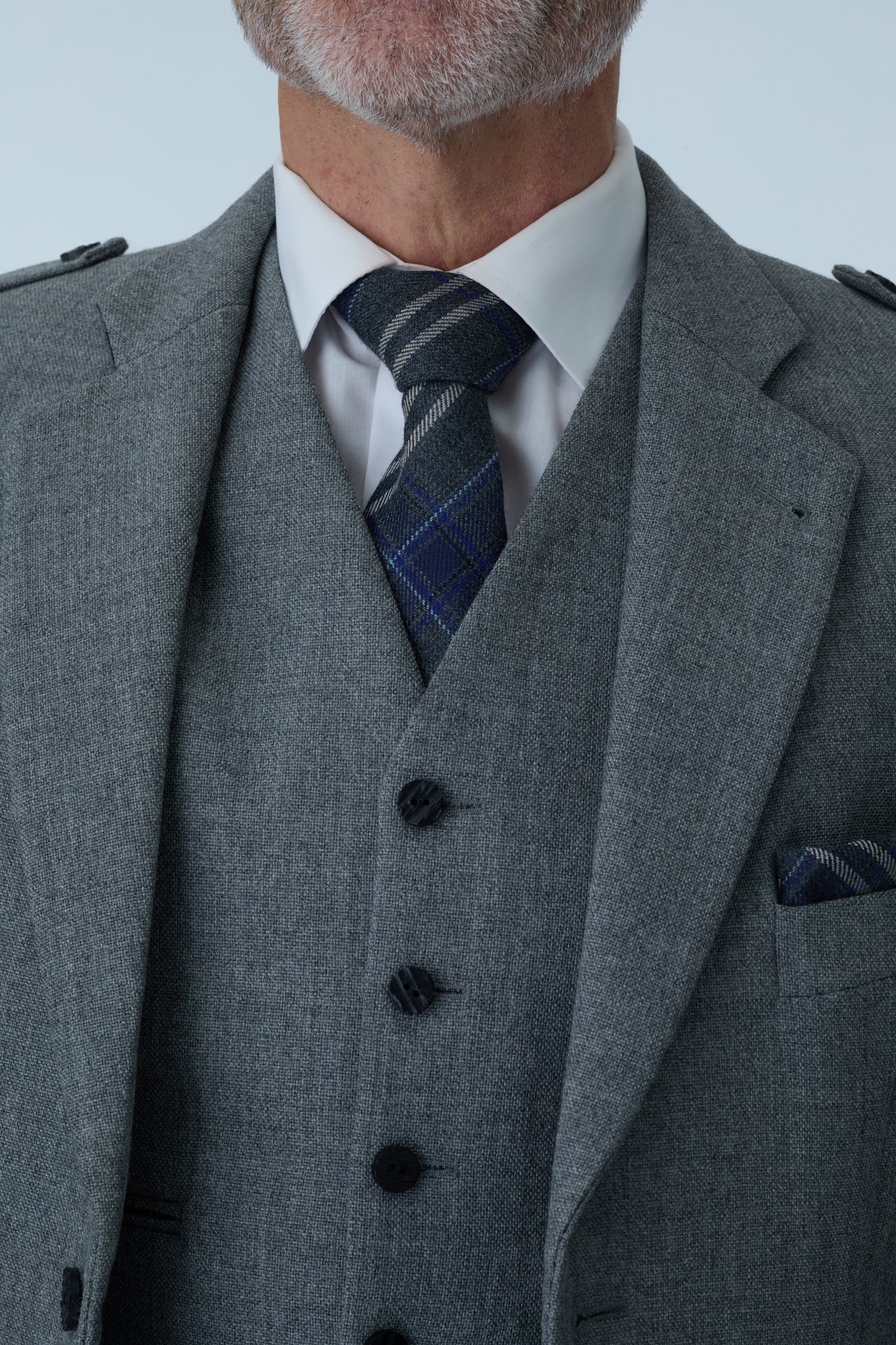 Gray tweed jacket with a patterned tie against a light gray background