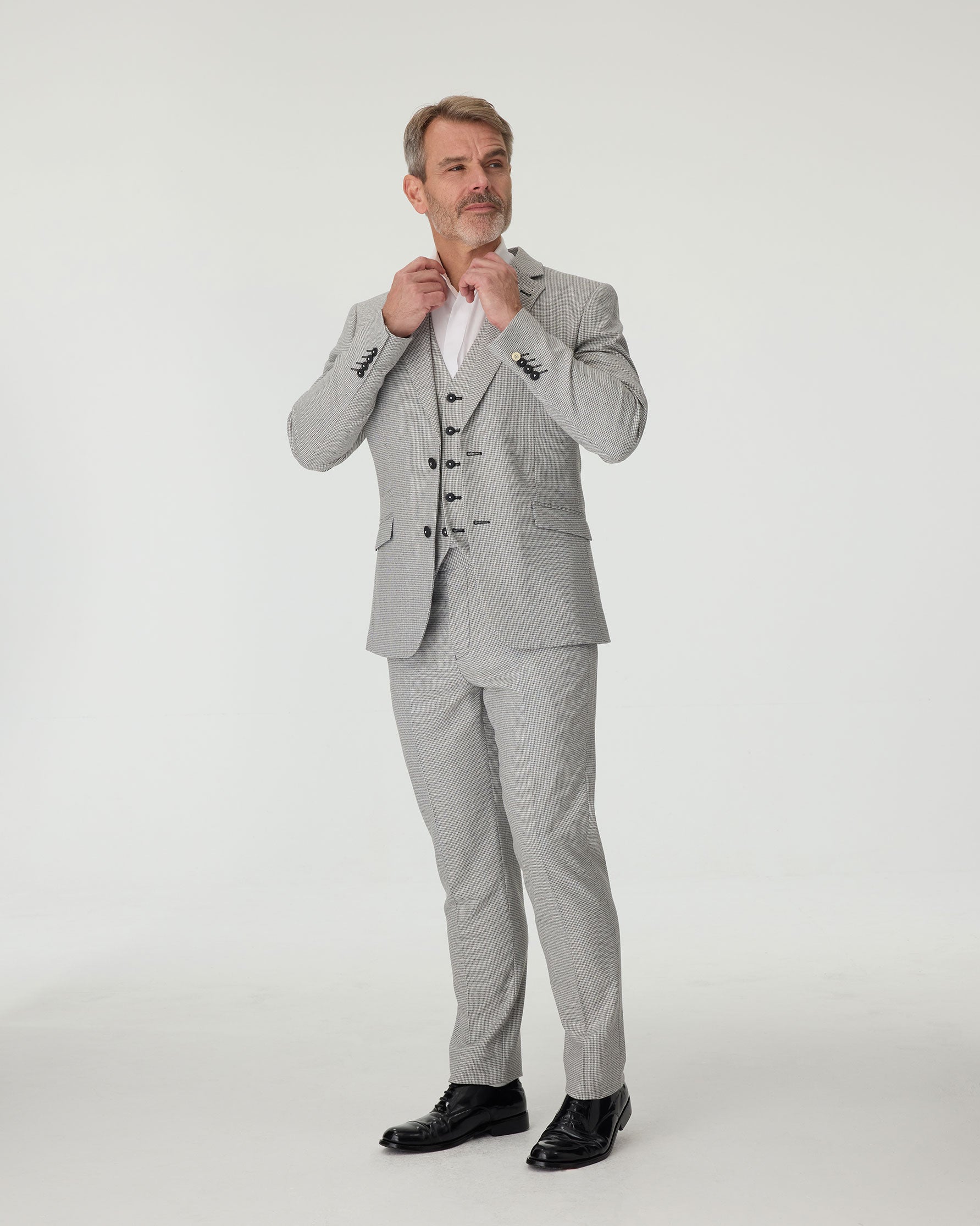 Man wearing a gray checkered suit with a white shirt on a white background