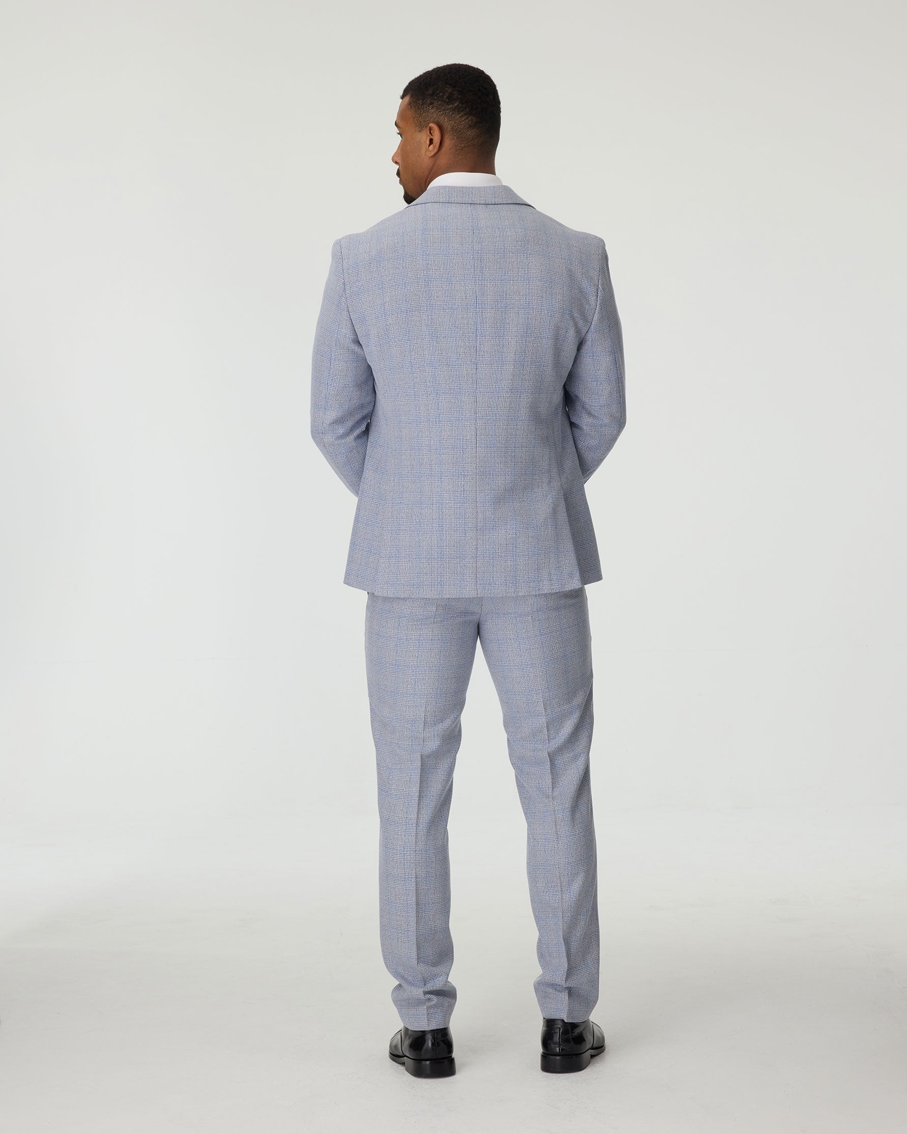 Man wearing a sky blue checkered suit standing against a white background