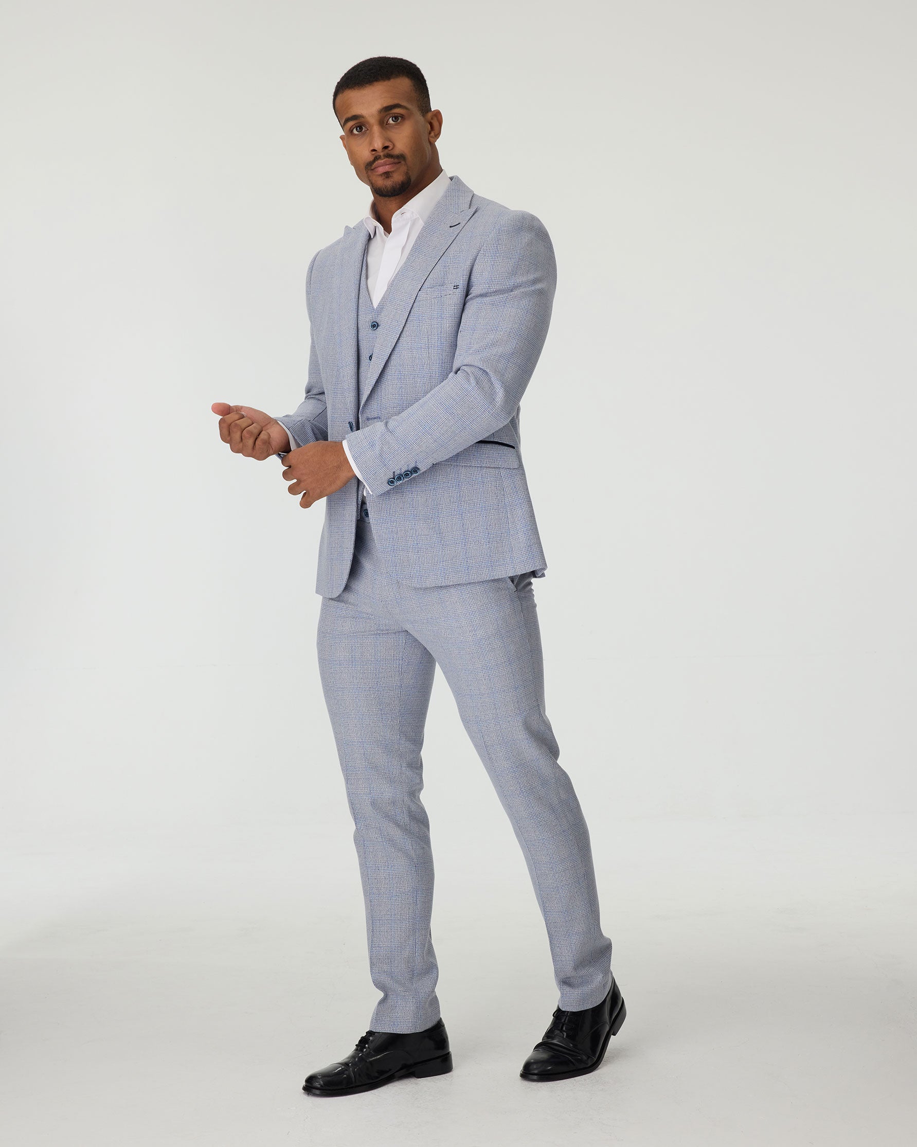 Man wearing a sky blue suit with a white shirt on a plain background