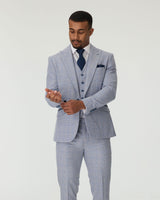 Man wearing a sky blue checkered suit with a white shirt and navy tie on a plain background